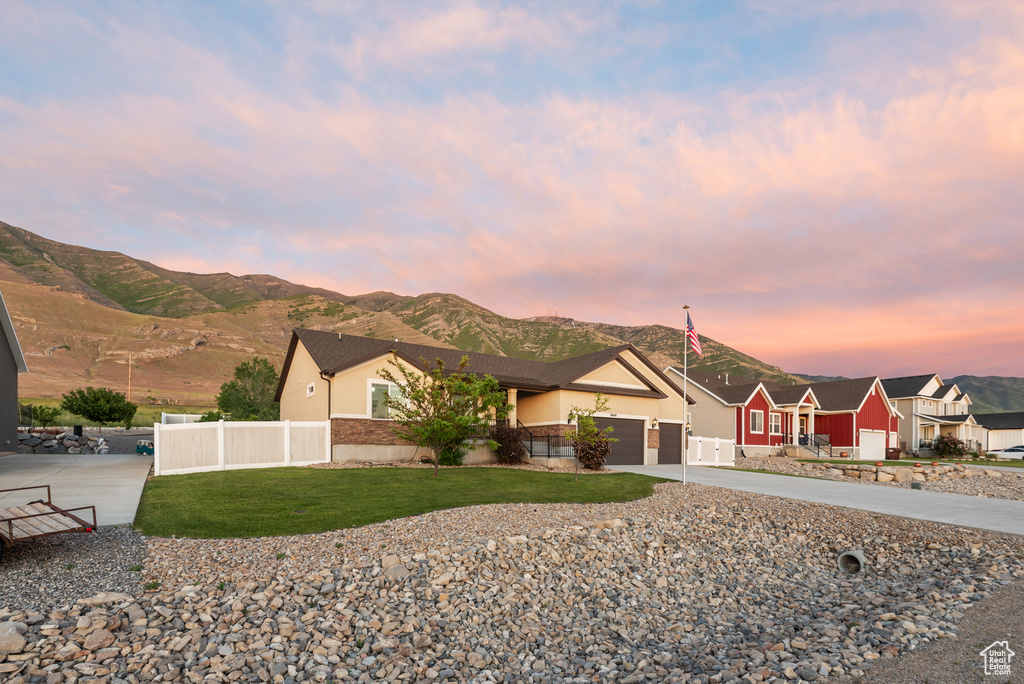 View of front of house with stucco siding, a mountain view, a garage, and driveway