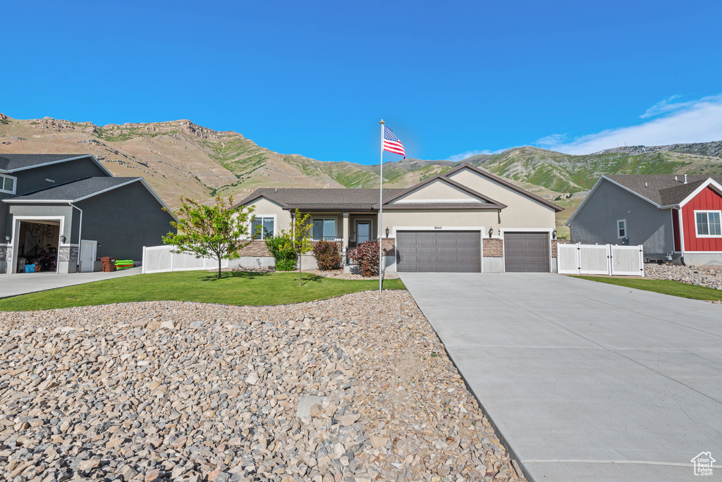 Single story home featuring a mountain view, driveway, an attached garage, stucco siding, and a gate