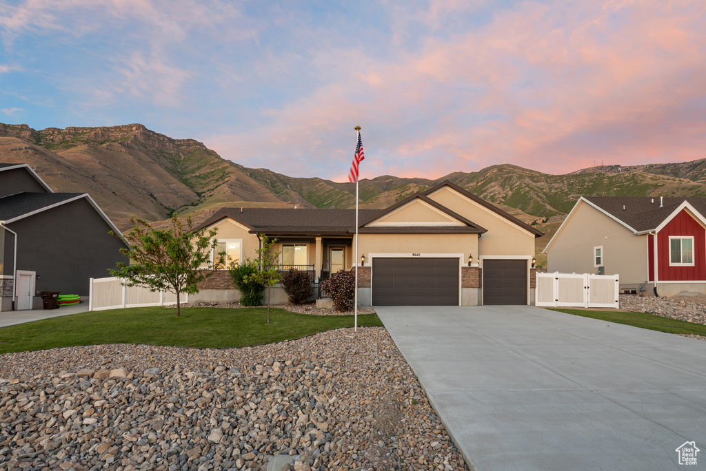 Ranch-style home featuring an attached garage, a mountain view, driveway, and stucco siding