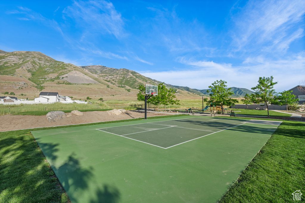 View of tennis court featuring a mountain view, community basketball court, and a yard