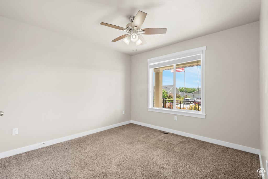 Carpeted empty room featuring baseboards and a ceiling fan