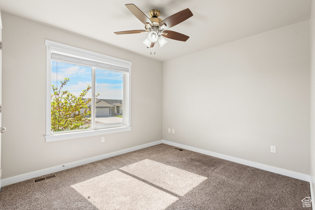 Spare room featuring carpet, baseboards, and a ceiling fan