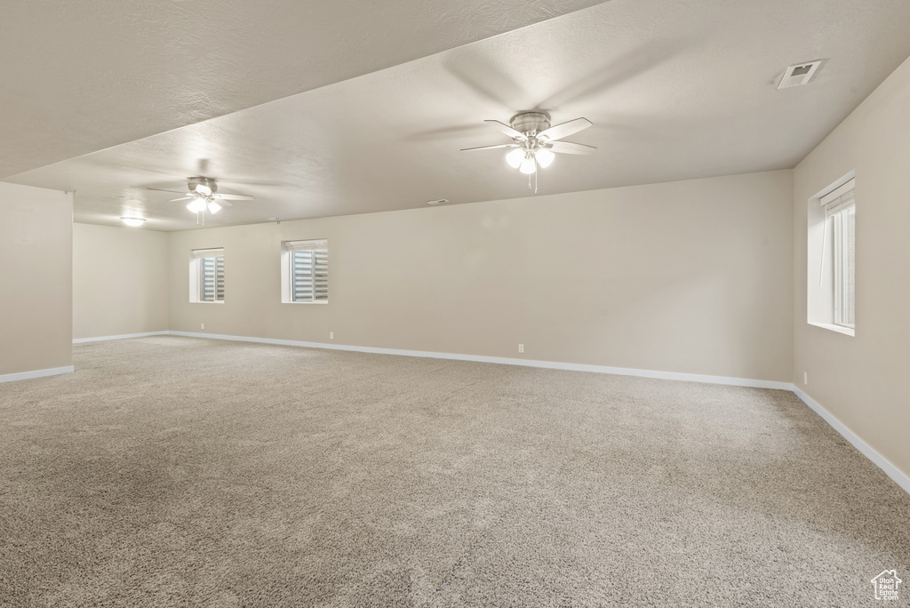 Empty room with ceiling fan, baseboards, and carpet floors