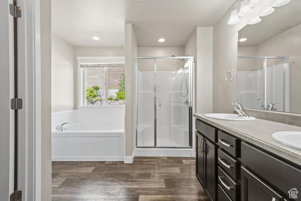 Full bathroom featuring a stall shower, wood finished floors, a garden tub, double vanity, and recessed lighting
