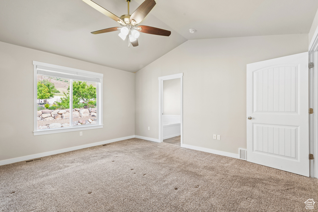 Unfurnished bedroom with lofted ceiling, carpet flooring, baseboards, ensuite bathroom, and ceiling fan