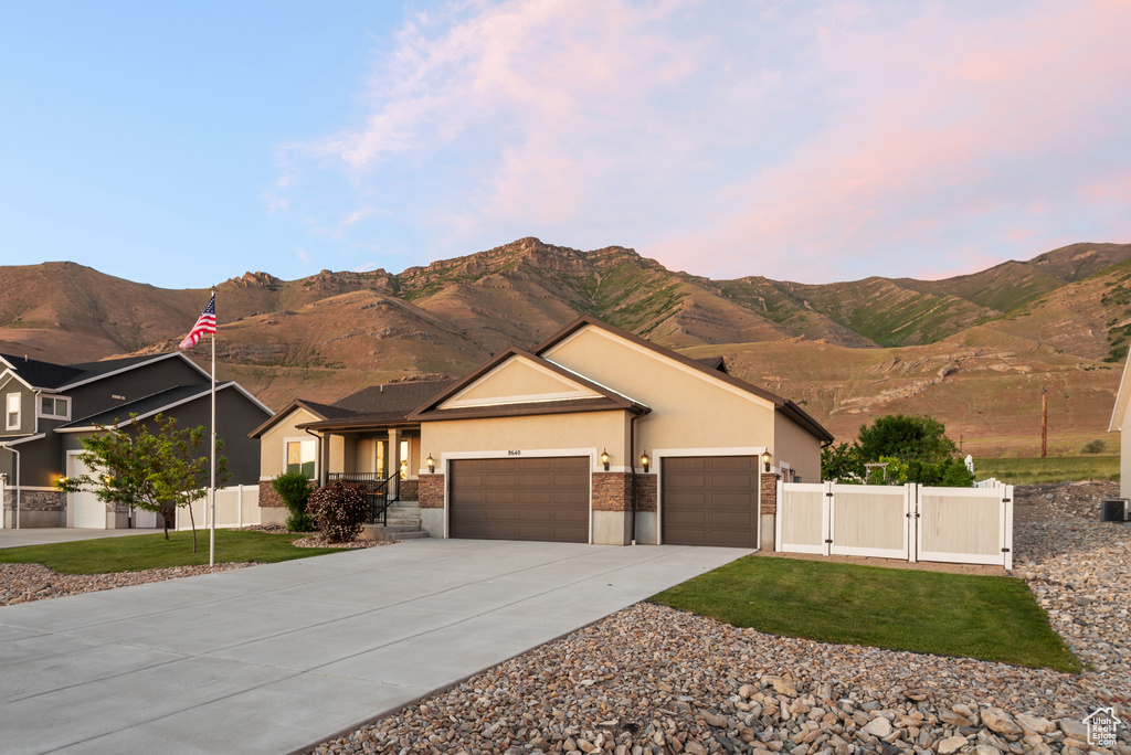 Single story home with a gate, an attached garage, stucco siding, and a mountain view