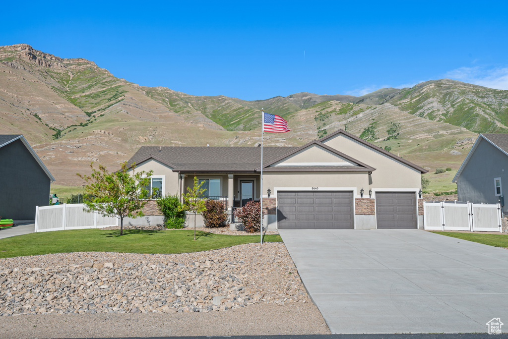 Single story home featuring a garage, stucco siding, driveway, a gate, and a mountain view