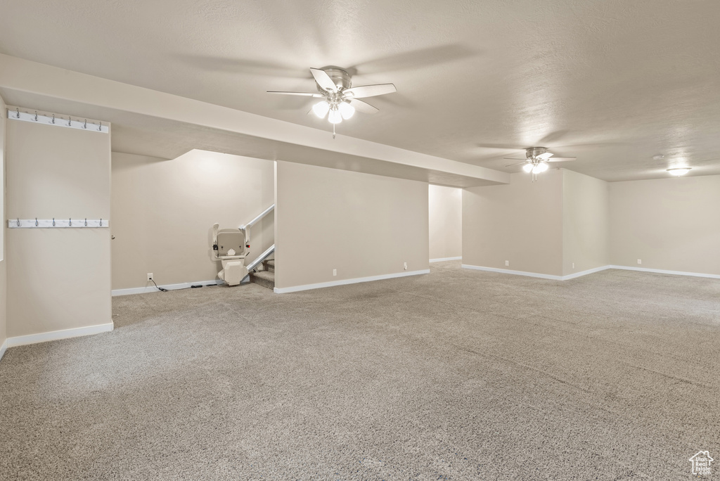Empty room with a ceiling fan, stairs, and carpet floors