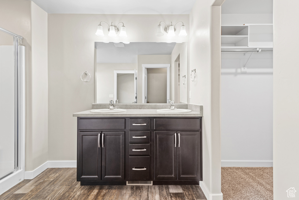 Full bath with a shower stall, double vanity, a walk in closet, and baseboards