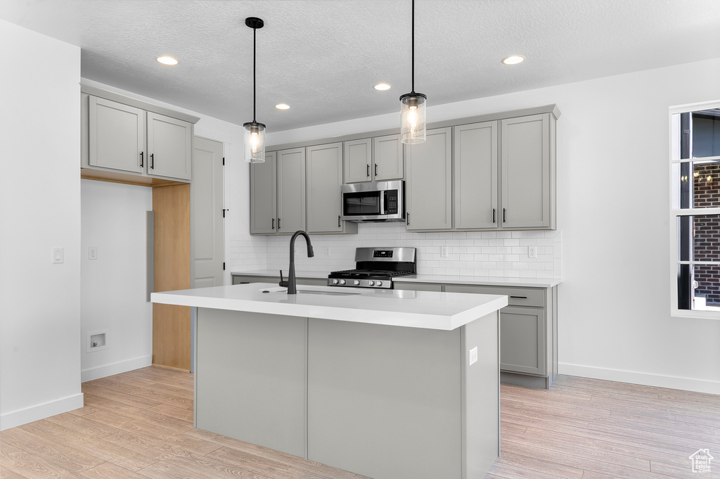 Kitchen featuring gray cabinets, stainless steel appliances, a sink, backsplash, and recessed lighting