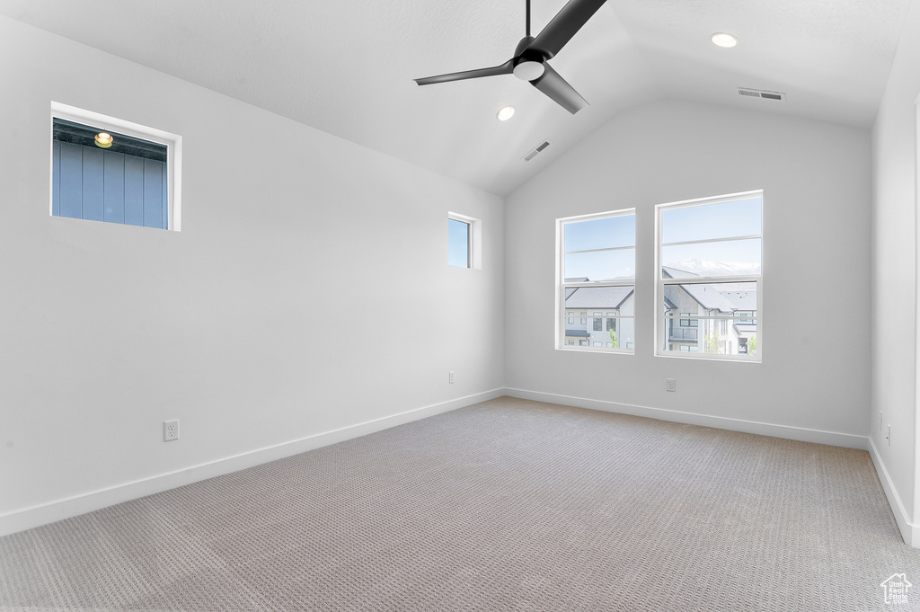 Empty room featuring light carpet, vaulted ceiling, ceiling fan, baseboards, and recessed lighting