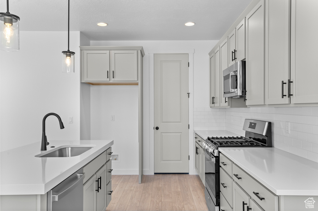Kitchen featuring stainless steel appliances, a sink, light wood-style floors, light countertops, and recessed lighting
