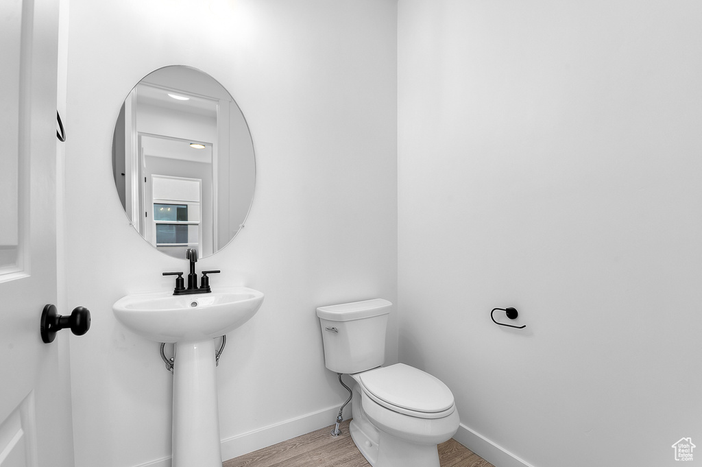 Half bath featuring baseboards, toilet, and wood finished floors