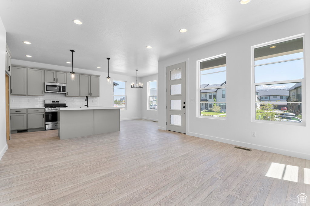Kitchen featuring appliances with stainless steel finishes, gray cabinets, open floor plan, light countertops, and recessed lighting