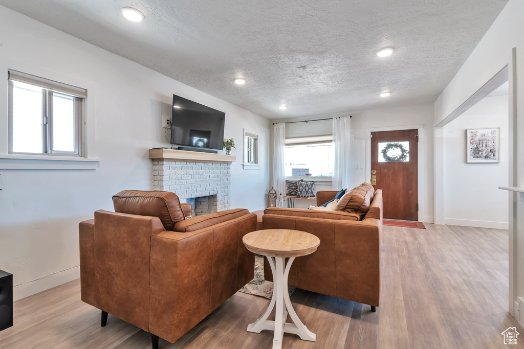 Living room featuring a textured ceiling, a fireplace, and light wood-type flooring