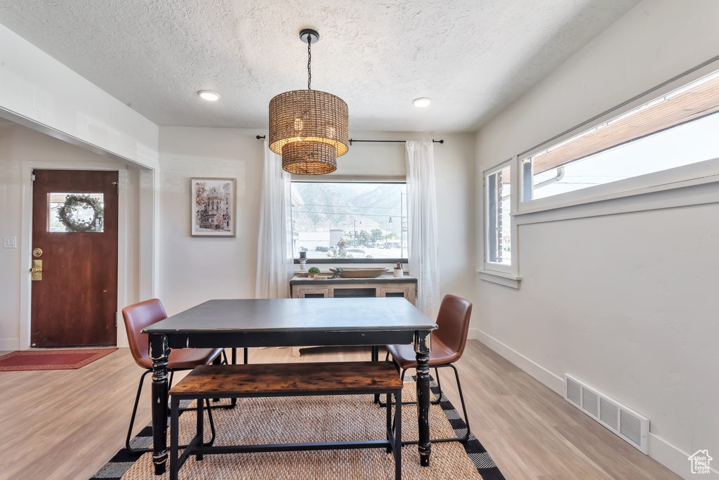 Dining area featuring a notable chandelier, a textured ceiling, and light wood-type flooring