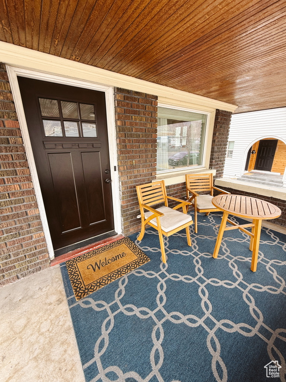 Entrance to property featuring a porch and brick siding