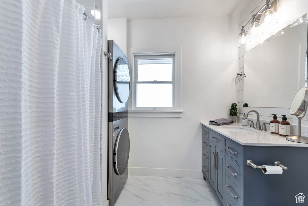 Bathroom with stacked washer and dryer, vanity, and curtained shower