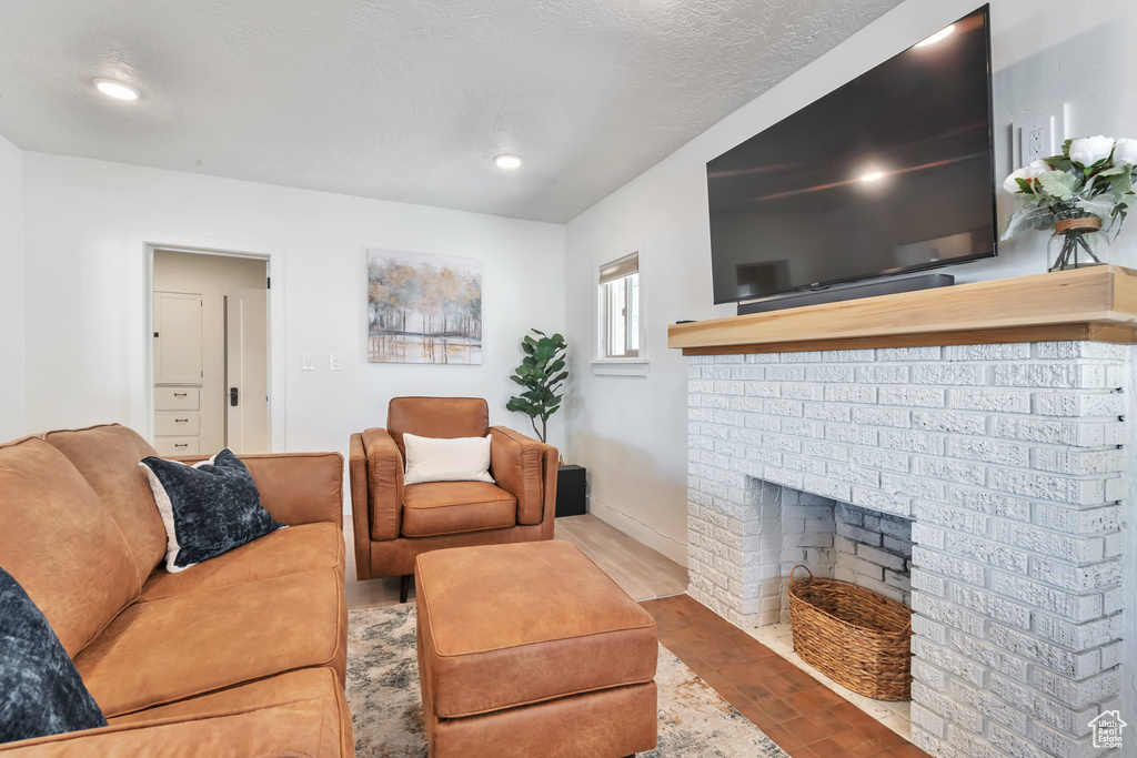 Living room featuring wood-type flooring, a fireplace, and a textured ceiling