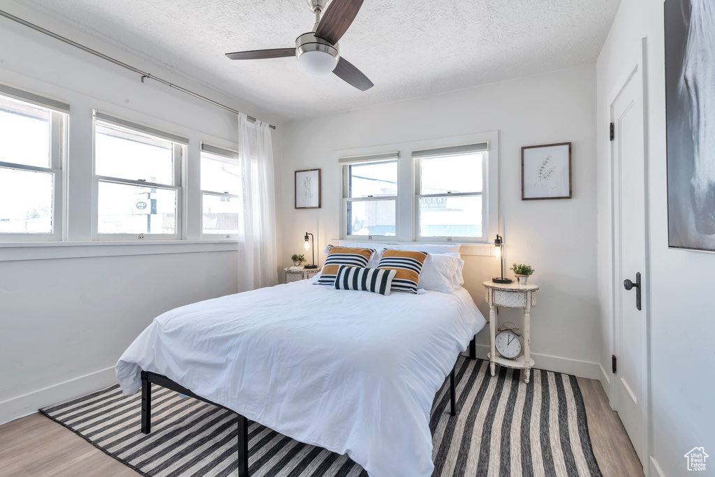 Bedroom with ceiling fan, light hardwood / wood-style flooring, and a textured ceiling
