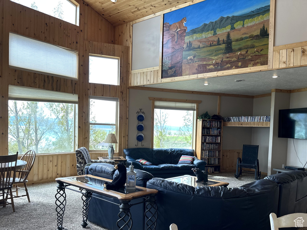 Living area featuring high vaulted ceiling, carpet flooring, and wood walls