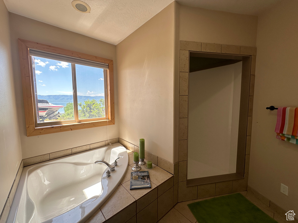 Full bath with a garden tub and a textured ceiling