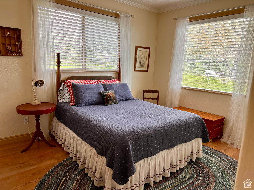 Bedroom featuring light wood-style flooring, multiple windows, and crown molding