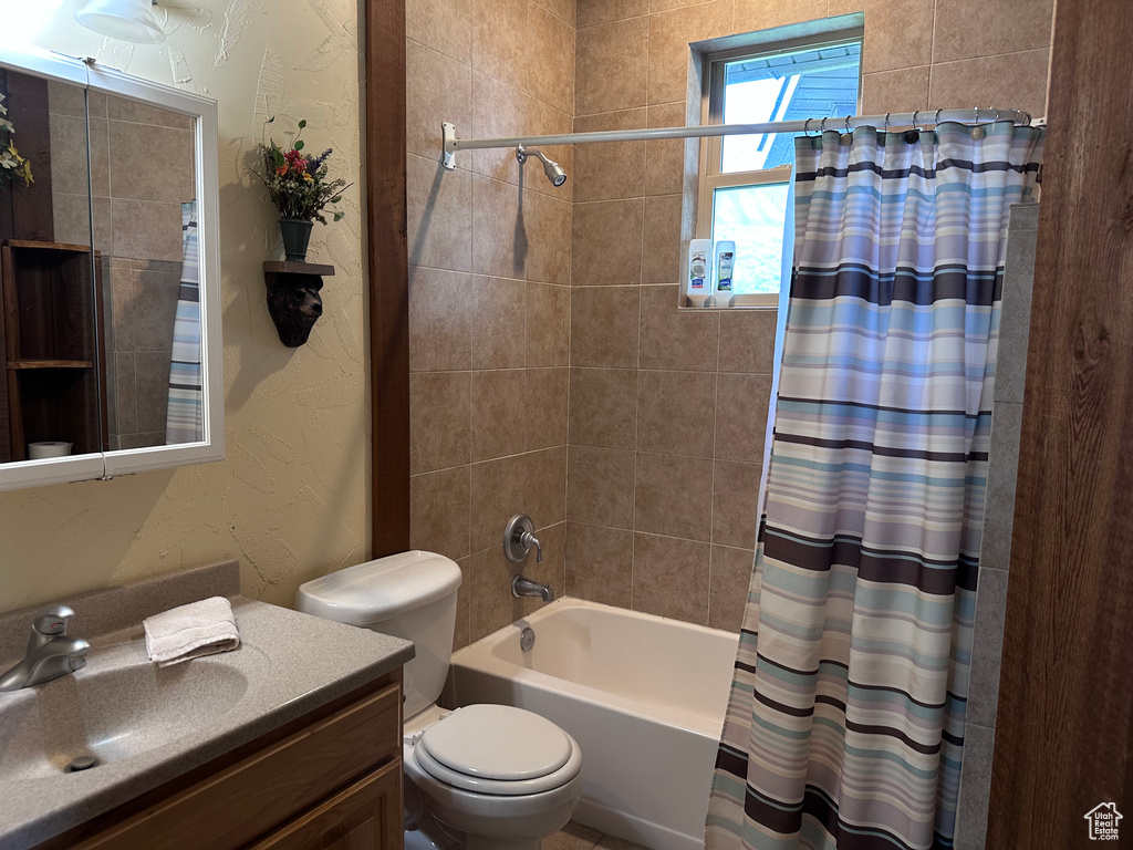 Full bathroom with toilet, vanity, shower / tub combo, and a textured wall