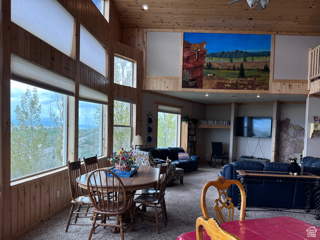 Dining space featuring high vaulted ceiling, carpet flooring, wooden walls, and wooden ceiling
