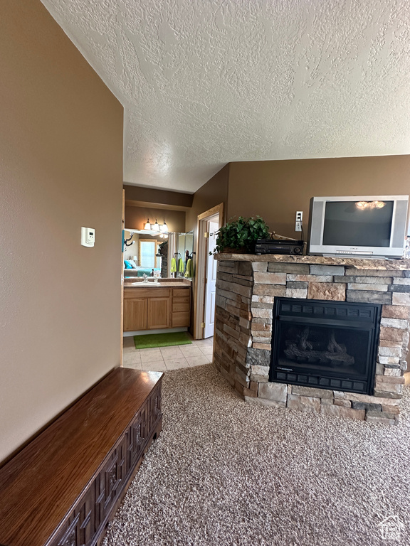 Living room featuring a fireplace, a textured ceiling, and light carpet