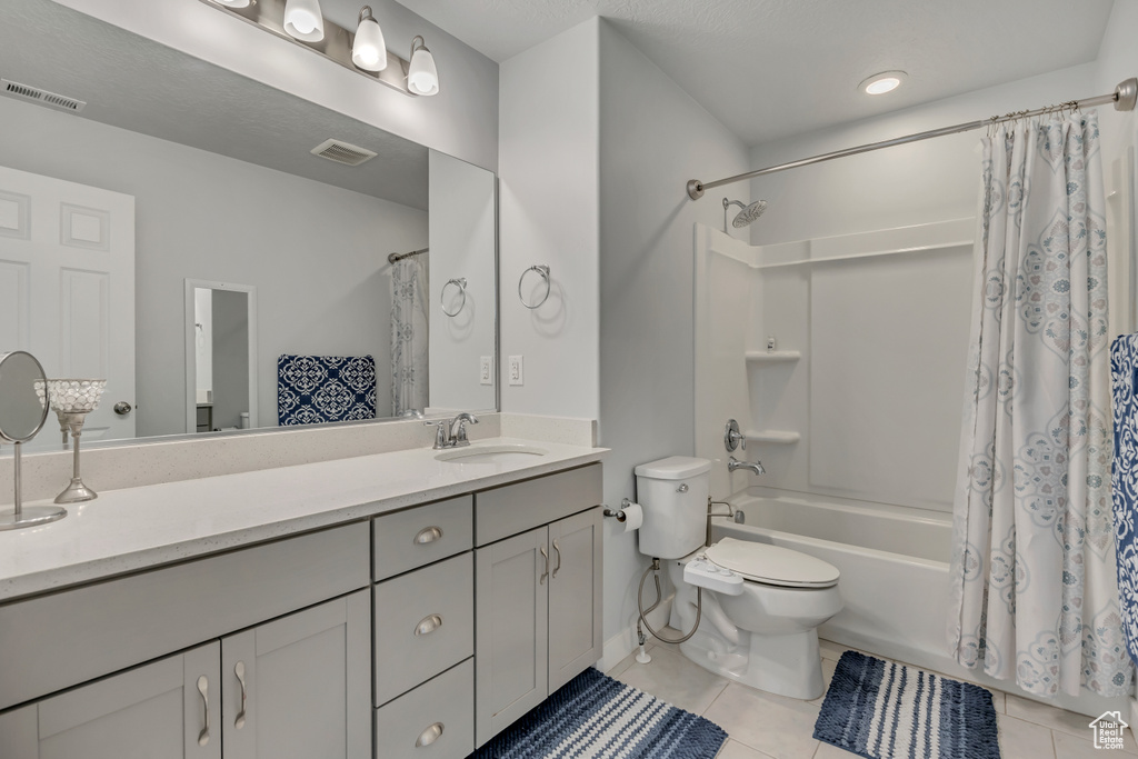 Bathroom featuring toilet, vanity, tile patterned floors, and shower / tub combo