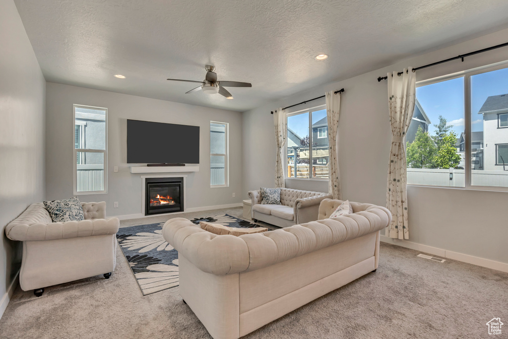 Carpeted living room featuring plenty of natural light, baseboards, a ceiling fan, recessed lighting, and a textured ceiling