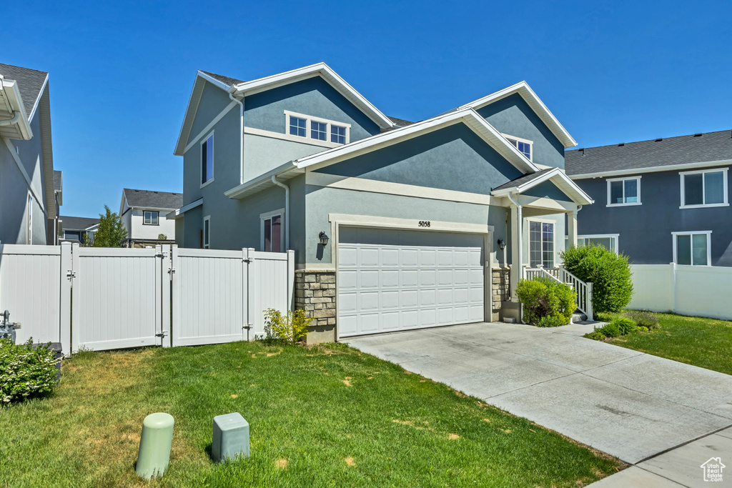 View of front of home with a gate, stucco siding, driveway, an attached garage, and stone siding