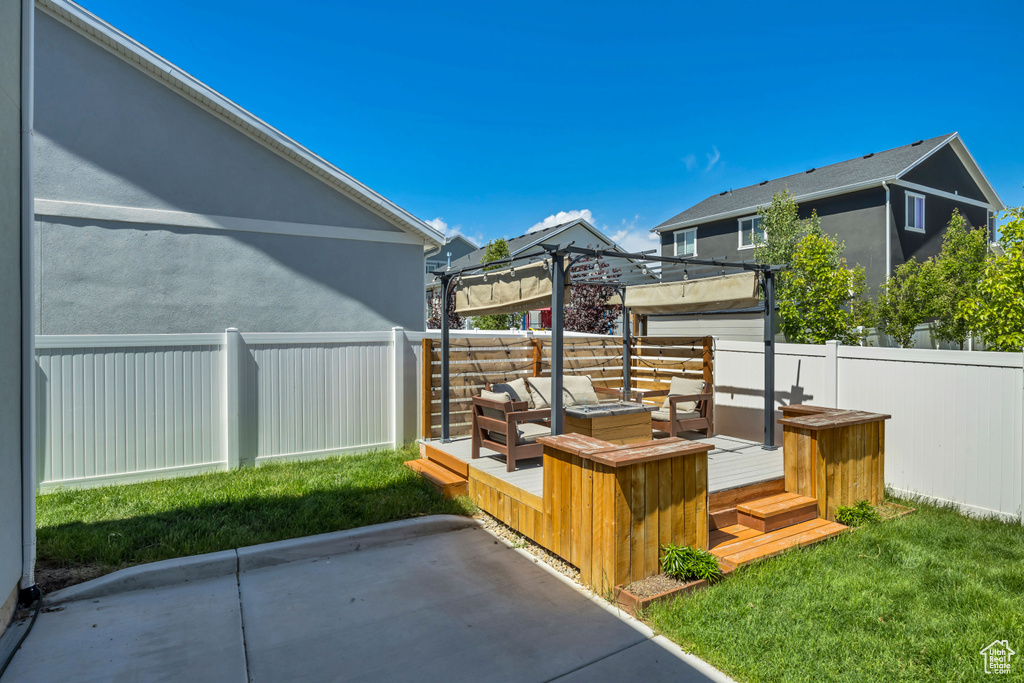 Fenced backyard with a wooden deck, a pergola, and a patio