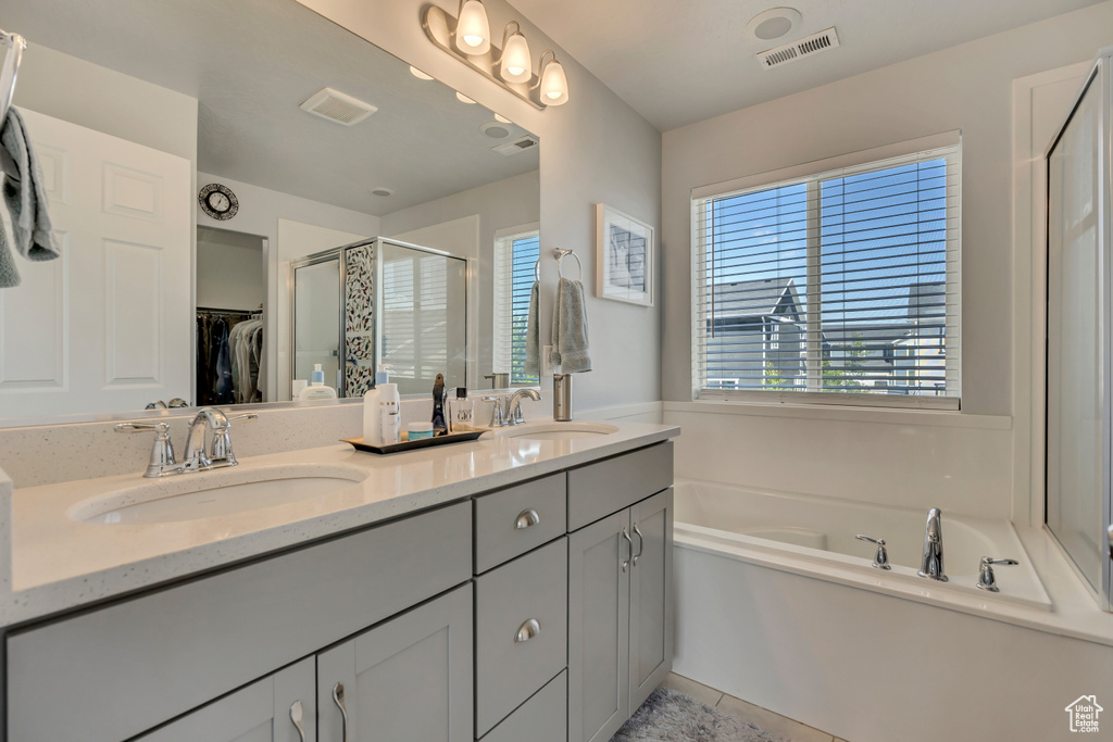 Full bathroom with a stall shower, double vanity, a garden tub, a spacious closet, and tile patterned floors