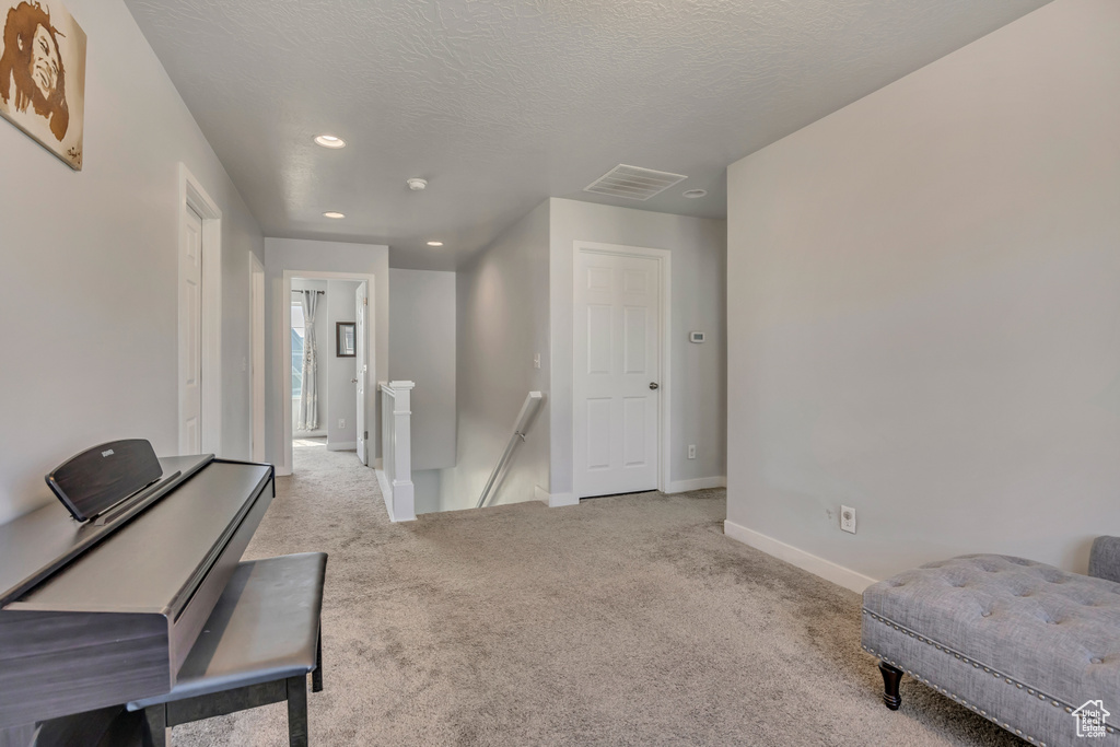 Living area featuring an upstairs landing, carpet, baseboards, recessed lighting, and a textured ceiling
