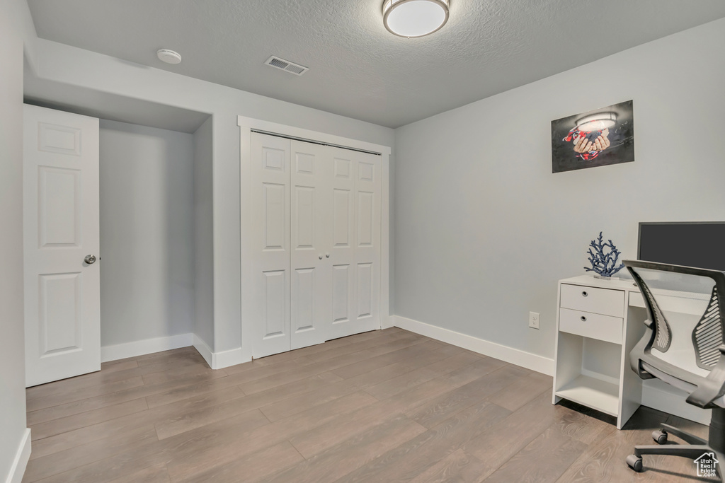 Home office featuring baseboards, wood finished floors, and a textured ceiling