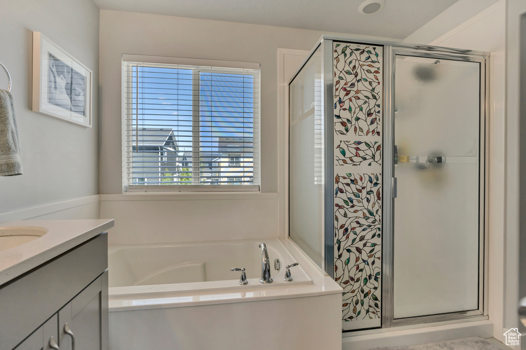 Full bathroom featuring a stall shower, a garden tub, and vanity