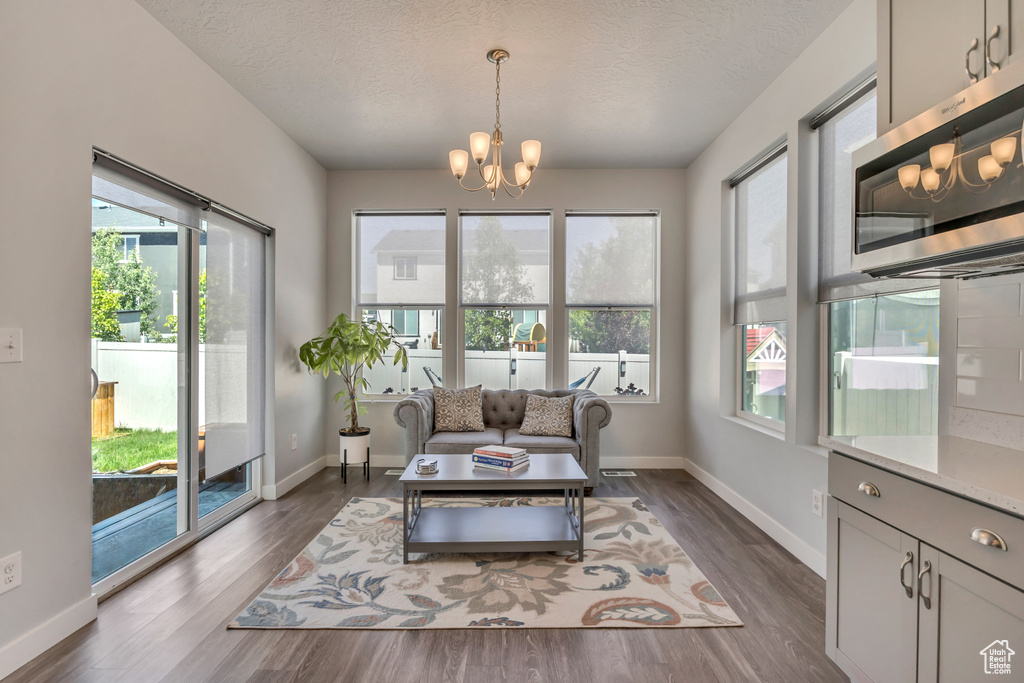Living area with a chandelier, a textured ceiling, dark wood finished floors, and plenty of natural light