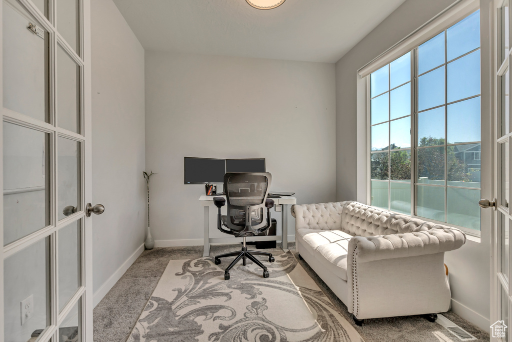 Carpeted home office with french doors and baseboards