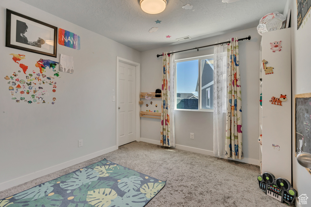 Bedroom featuring carpet floors, a textured ceiling, and baseboards