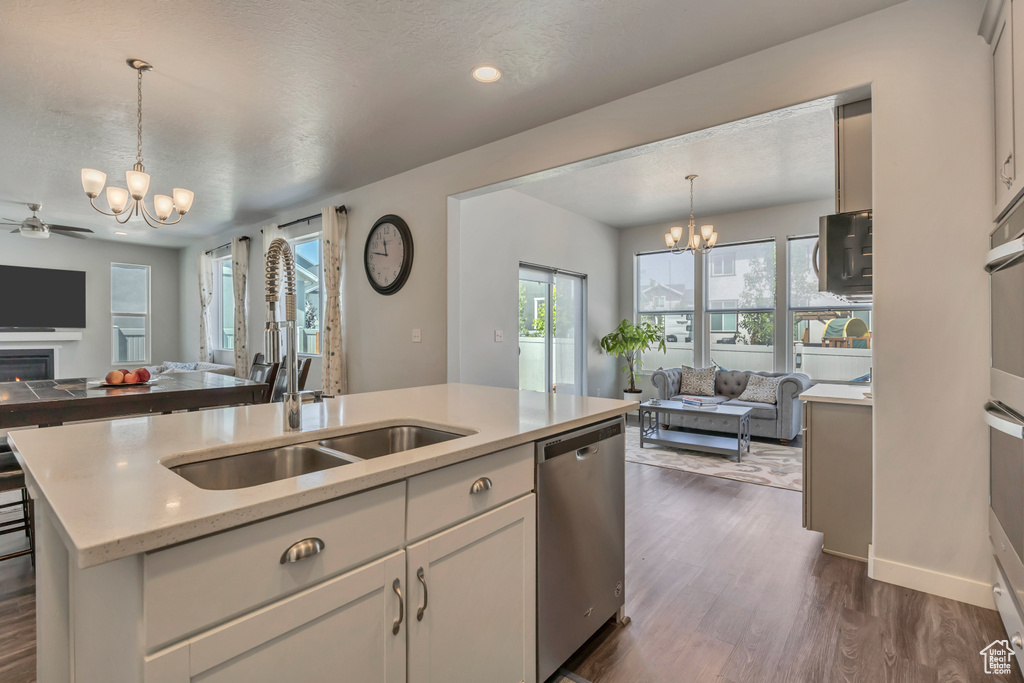 Kitchen featuring a chandelier, open floor plan, stainless steel dishwasher, a sink, and recessed lighting