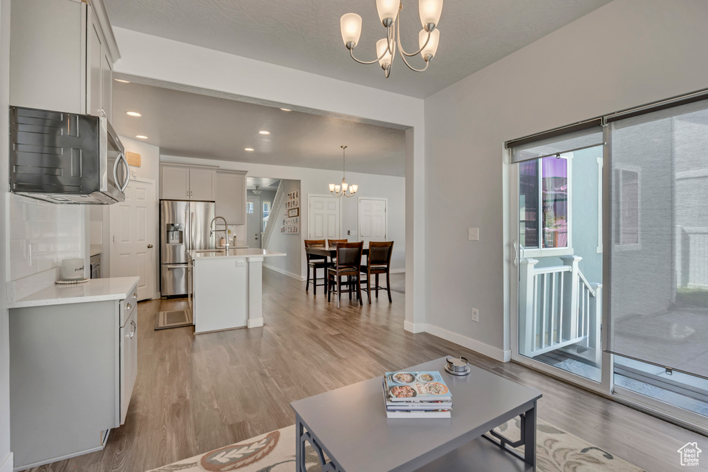 Living room featuring a chandelier, light wood finished floors, baseboards, and recessed lighting