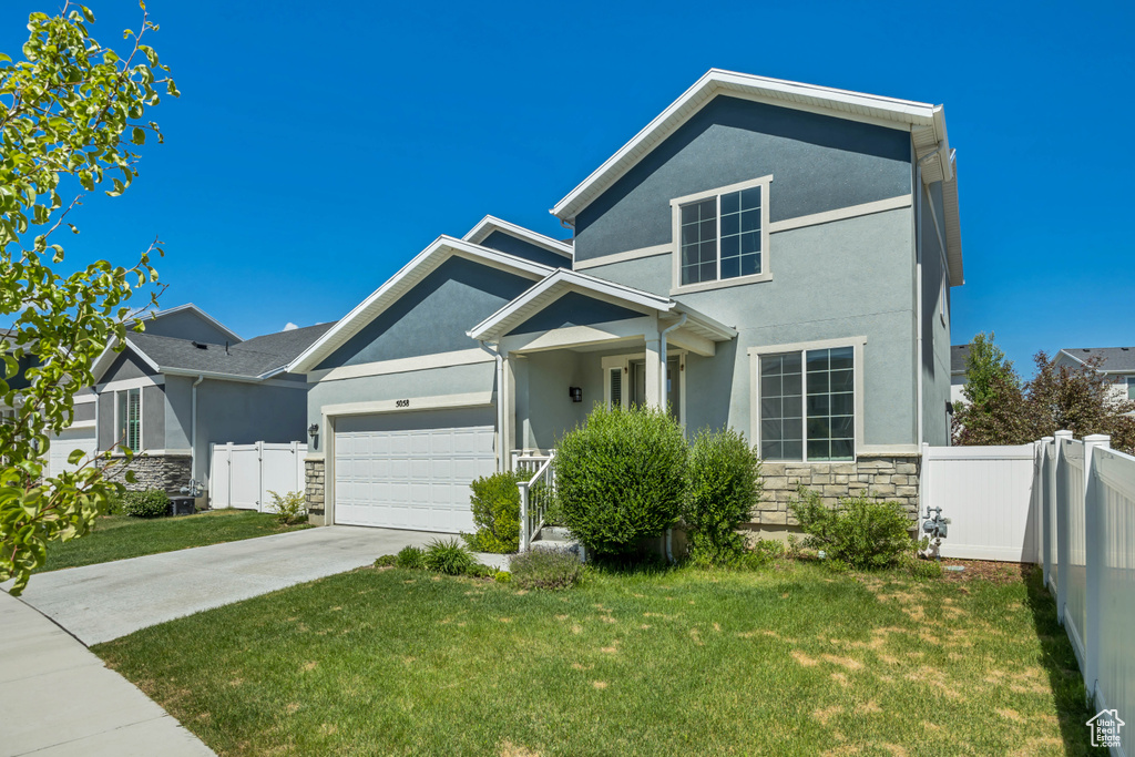 View of front facade featuring stone siding, stucco siding, an attached garage, and driveway