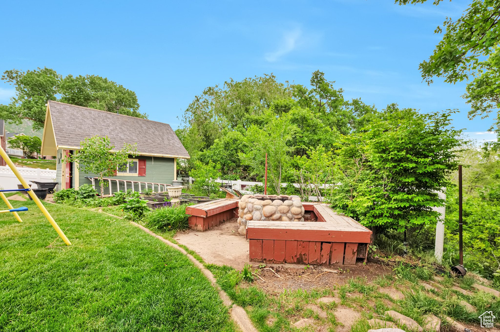 View of green lawn featuring an outdoor structure and a vegetable garden