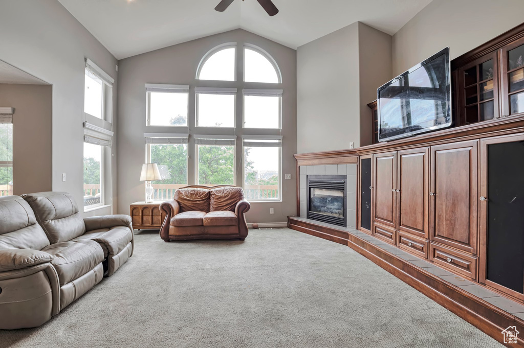Carpeted living area with ceiling fan, high vaulted ceiling, and a fireplace