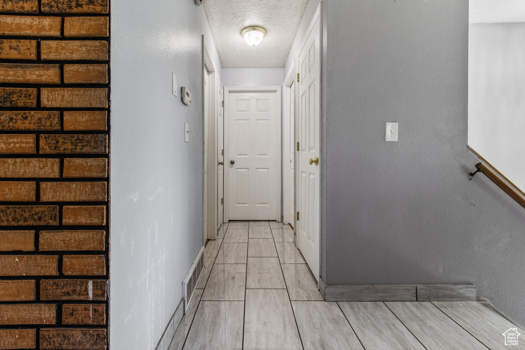 Hallway featuring baseboards and a textured ceiling