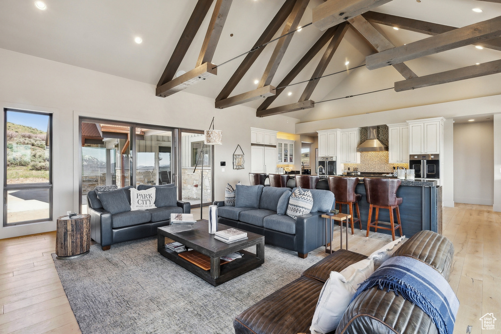 Living room featuring light wood finished floors, recessed lighting, high vaulted ceiling, and beam ceiling