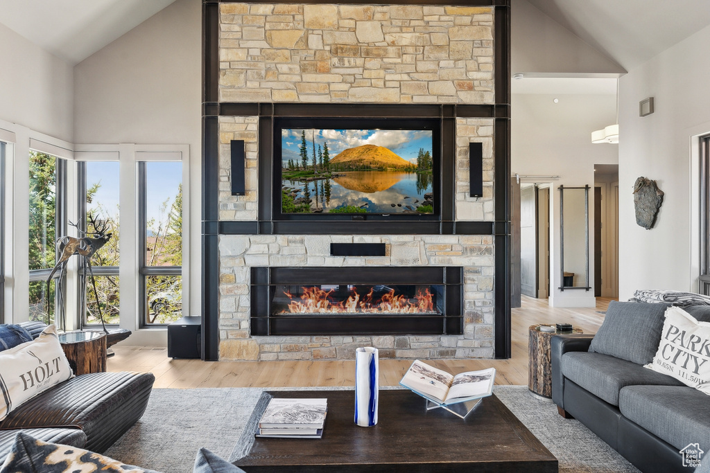 Living room with a fireplace, high vaulted ceiling, and wood finished floors