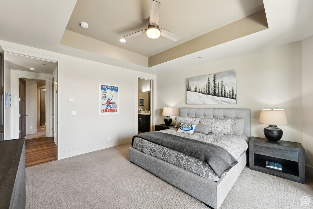 Carpeted bedroom featuring a tray ceiling, recessed lighting, baseboards, ceiling fan, and connected bathroom